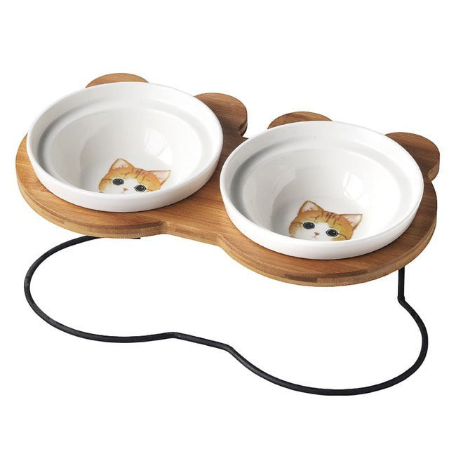 Furlouve Ergonomic Cat Dining Stand with two white ceramic bowls featuring orange tabby cat faces on a bamboo stand.