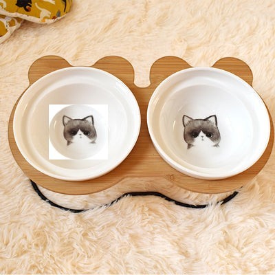 Furlouve Ergonomic Cat Dining Stand with two white ceramic bowls featuring grumpy cat faces on a bamboo stand.