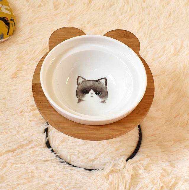 Furlouve Ergonomic Cat Dining Stand with a ceramic bowl featuring a cute grey and white cat face design.